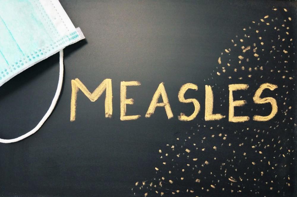 Measles written on chalkboard with mask