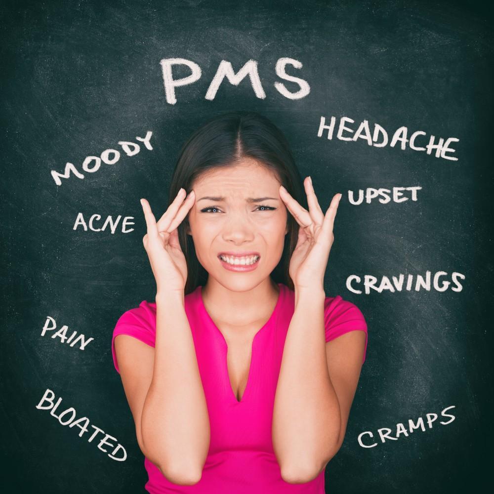 Woman experiencing PMS symptoms on chalkboard background