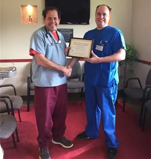 Two healthcare professionals holding a certificate