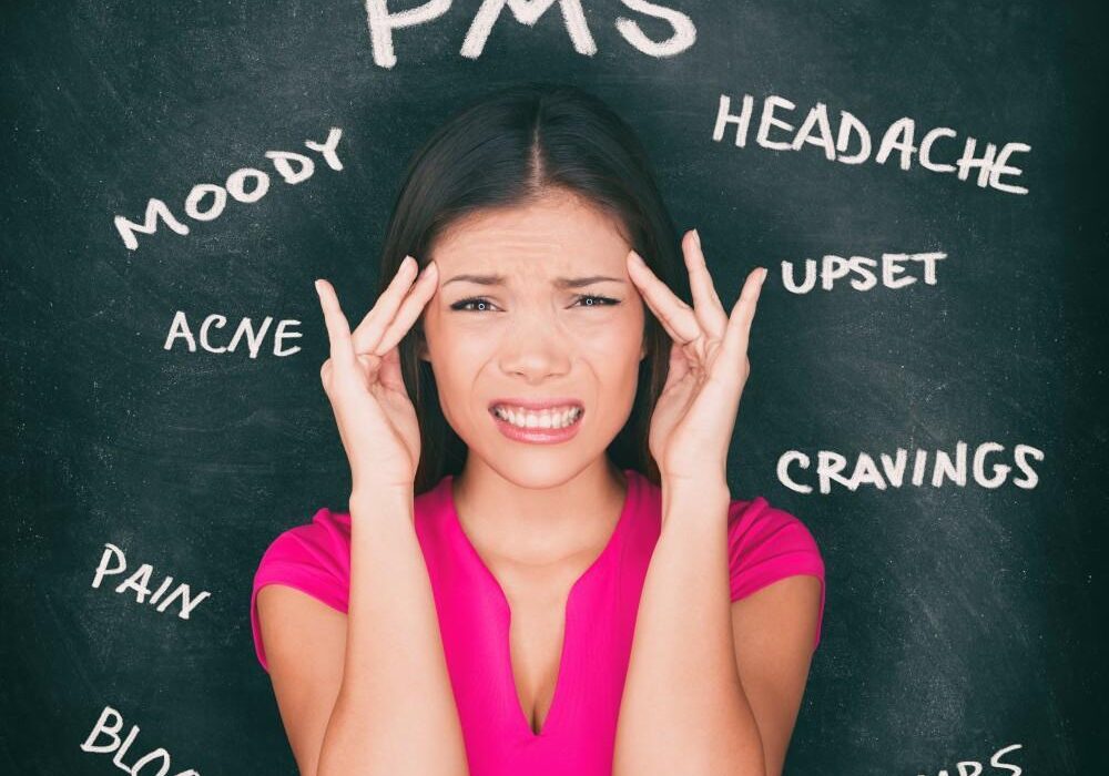 Woman experiencing PMS symptoms on chalkboard background